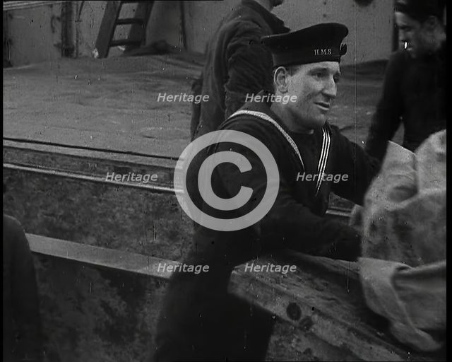 Several Male Crew, Including One from the Royal Navy, Inspecting the Cargo of a Large Vessel, 1939. Creator: British Pathe Ltd.
