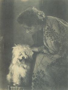 Seated woman petting her white dog, c1900. Creator: Virginia M Prall