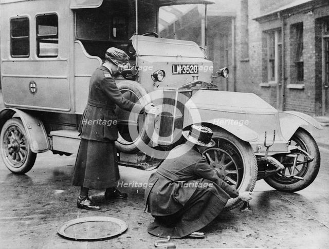 Siddeley Deasy ambulance 1911, women changing wheel. Creator: Unknown.