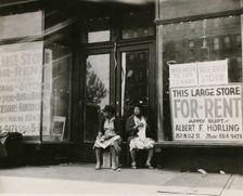 Sidewalk sitters. Two women sitting in doorway of empty storefront that is being..., ca. 1930s. Creator: Unknown