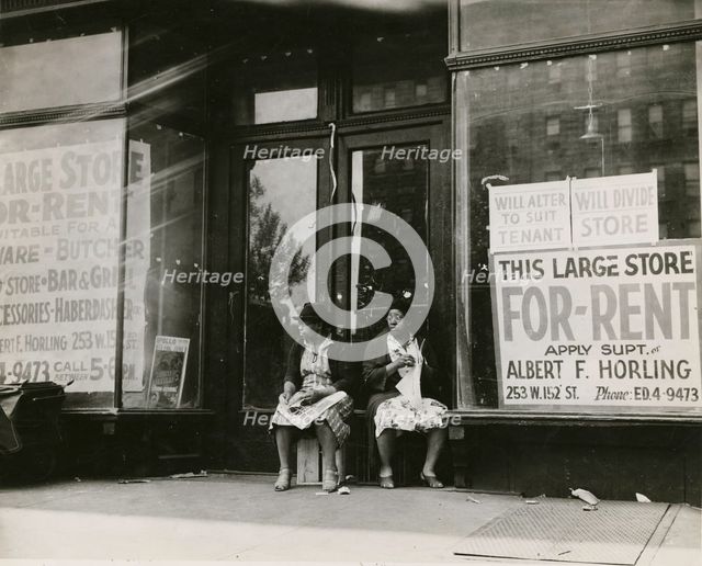 Sidewalk sitters. Two women sitting in doorway of empty storefront that is being..., ca. 1930s. Creator: Unknown.