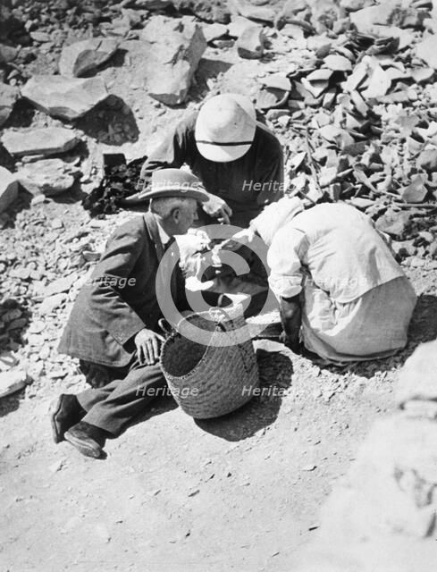 Sifting the dust from the floor of the Tomb of Tutankhamun, Valley of the Kings, Egypt, 1922. Creator: Harry Burton.