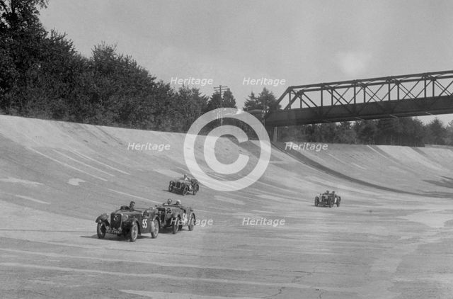 Singers of TW Fassett and Alf Langley and an MG racing at a MCC meeting, Brooklands, Surrey, 1933. Artist: Bill Brunell.