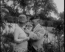 Sir Harry Lauder Giving Flowers to His Wife, Lady Ann Lauder, at Home in Scotland, 1920s. Creator: British Pathe Ltd