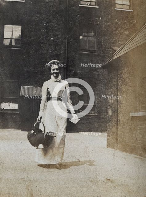 St Bartholomew's Hospital, London: a smiling nurse carrying a coal scuttle, c1890. Creator: Unknown.