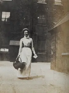 St Bartholomew's Hospital, London: a smiling nurse carrying a coal scuttle, c1890. Creator: Unknown