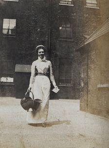 St Bartholomew's Hospital, London: a smiling nurse carrying a coal scuttle, c1890. Creator: Unknown