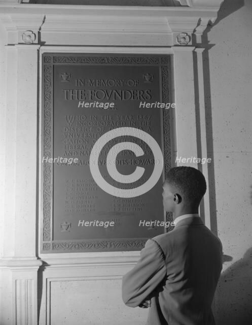 Student reading bronze plaque in library of Howard University, Washington, D.C., 1942. Creator: Gordon Parks.