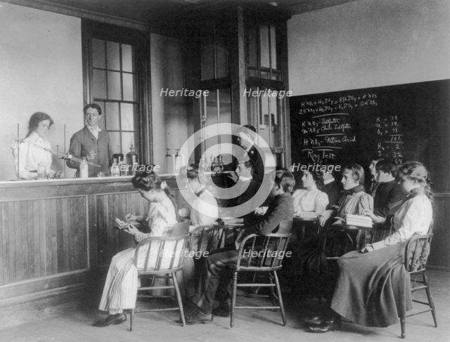 Students in a chemistry class observing others conducting an experiment...Washington DC, (1899?). Creator: Frances Benjamin Johnston.