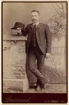 Studio portrait of a man holding a hat, about 1885. Creator: WH Greenwood