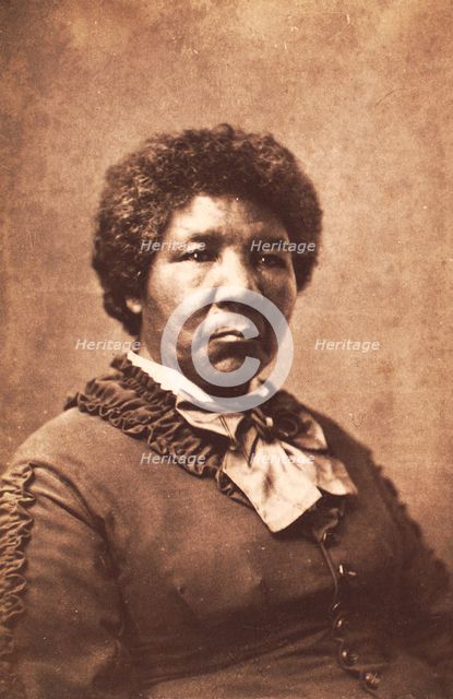 Studio portrait of unidentified woman dressed in a rouched jacket and large striped..., c1870-c1879. Creator: Unknown.