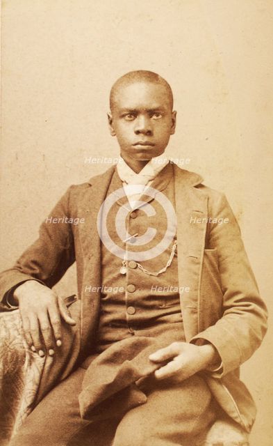 Studio portrait of unidentified seated young man, holding cap, c1880-c1889 . Creator: A. H. Plecker.