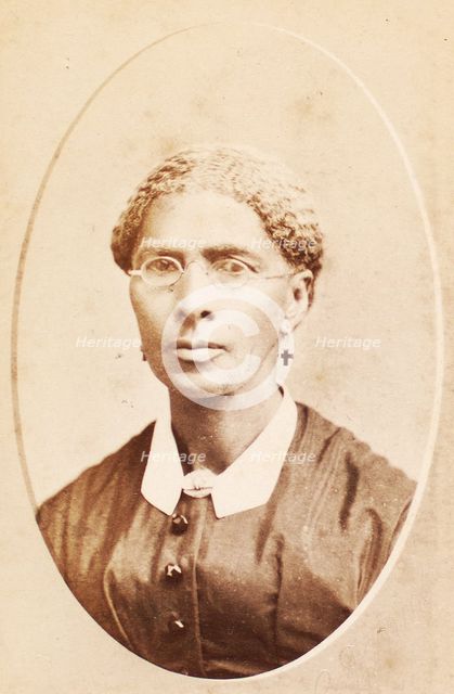 Studio portrait of woman wearing glasses and cross-shaped earrings, c1880-c1889. Creator: George Daniels Morse.