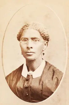 Studio portrait of woman wearing glasses and cross-shaped earrings, c1880-c1889. Creator: George Daniels Morse