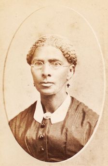 Studio portrait of woman wearing glasses and cross-shaped earrings, c1880-c1889. Creator: George Daniels Morse