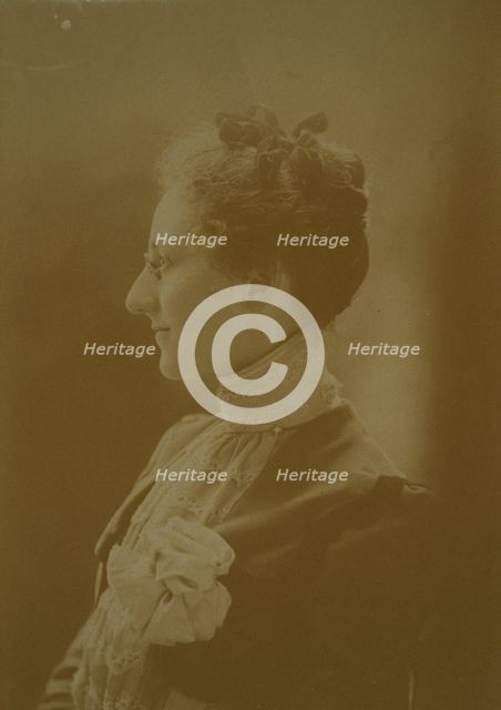 Studio portrait of young woman in white dress posed as if holding flowering tree branch, c1900. Creator: Unknown.