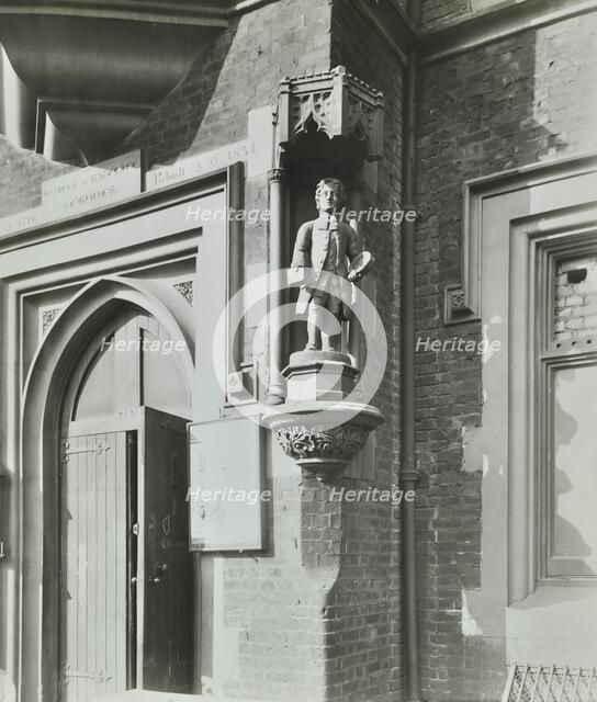 Statue of a boy scholar beside the door, Hamlet of Ratcliff Schools, Stepney, London, 1945. Artist: Unknown.