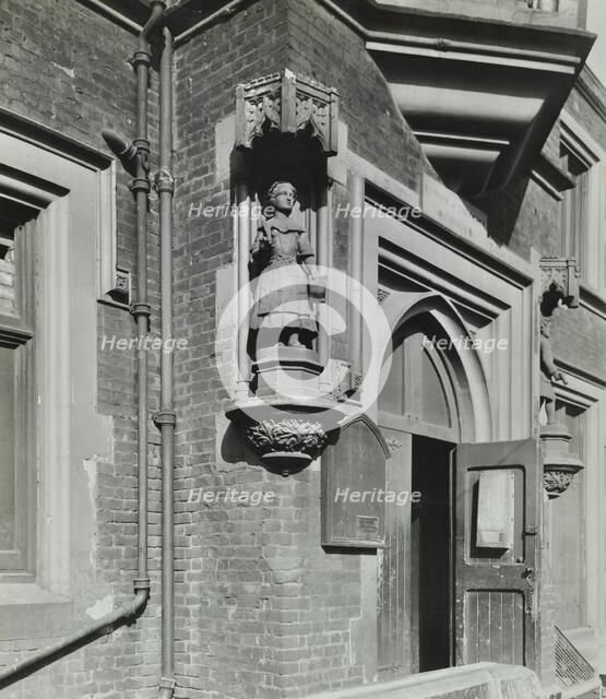 Statue of a girl scholar beside the door, Hamlet of Ratcliff Schools, Stepney, London, 1945. Artist: Unknown.