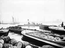Steam tug moving between barges on the Thames, London, c1905