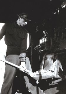 Stoker putting coal to a steam train engine