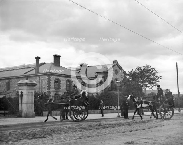 Street scene with horse carriages - possibly Ireland, 1898. Creator: Robert Augustus Henry L'Estrange.