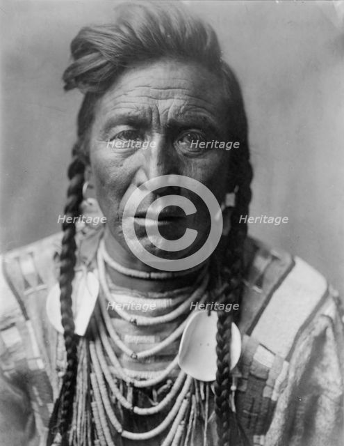 Strike On his Head, Crow Indian, Montana, head-and-shoulders portrait, facing front, loose..., c1908 Creator: Edward Sheriff Curtis.