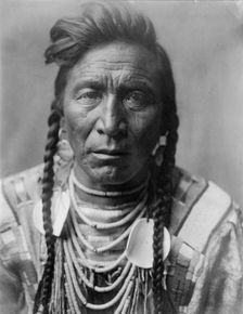 Strike On his Head, Crow Indian, Montana, head-and-shoulders portrait, facing front, loose..., c1908 Creator: Edward Sheriff Curtis