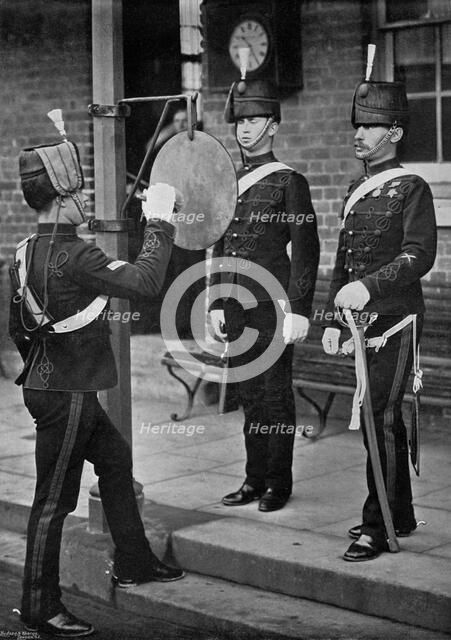 Striking the gong at the main gate of the Aldershot cavalry barracks, Hampshire, 1896. Artist: Gregory & Co