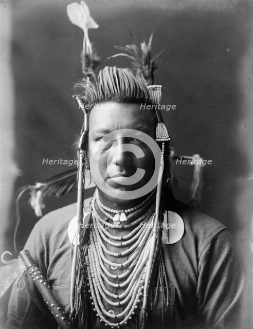 Swallow Bird, Crow Indian, Montana, head-and-shoulders portrait, facing front, painted..., c1908. Creator: Edward Sheriff Curtis.