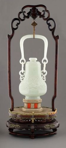 Swing handle vase with mask design on wooden stand, 19th century. Creator: Unknown