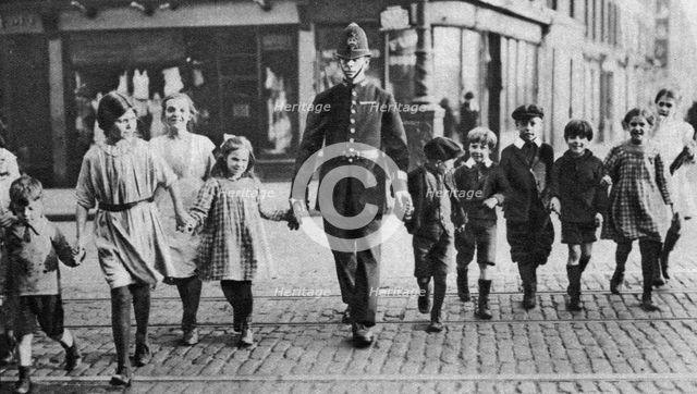 Policeman helping schoolchildren across the road, East End, London, 1926-1927. Artist: Unknown