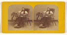 Portrait of Charles H. Barnes, Hardwick, Mass. seated in handicapped-style chair making ..., 1870s. Creator: George T Putnam