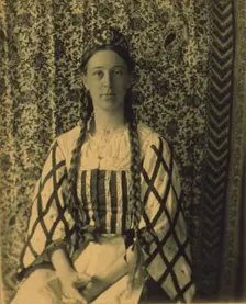 Portrait of a woman with braids in front of a paisley backdrop, c1900. Creator: Frances S. Allen