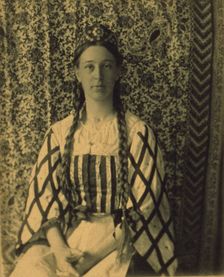 Portrait of a woman with braids in front of a paisley backdrop, c1900. Creator: Frances S. Allen