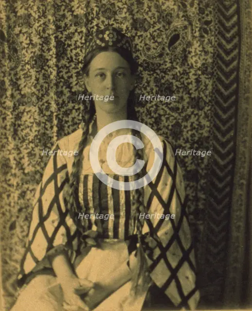 Portrait of a woman with braids in front of a paisley backdrop, c1900. Creator: Frances S. Allen.