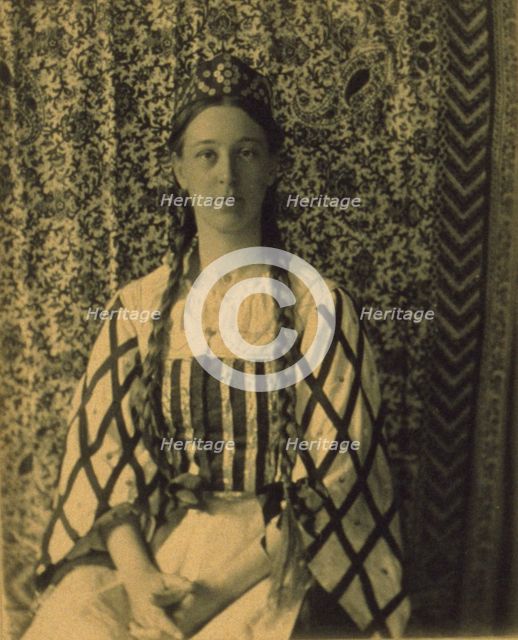 Portrait of a woman with braids in front of a paisley backdrop, c1900. Creator: Frances S. Allen.