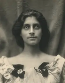Portrait of a woman in a floral dress adorned with diamond brooches and bows, c1900. Creator: Virginia M Prall