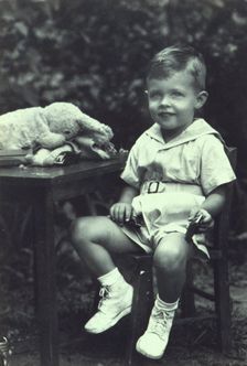 Portrait of a young boy seated at an outdoor table, facing front, between 1940 and 1950. Creator: Joseph Woodson Whitesell