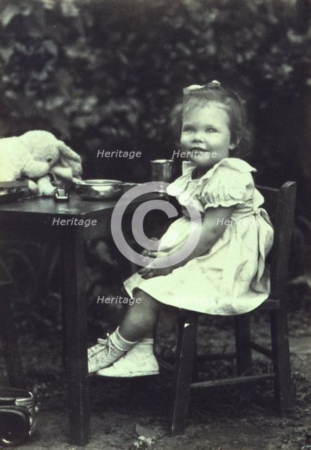 Portrait of a young girl seated at an outdoor table, facing front, between 1940 and 1950. Creator: Joseph Woodson Whitesell.