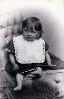 Portrait of a little girl in a big chair, c1910