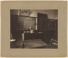 Portrait of a male mathematics teacher with moustache seated at his classroom desk, about 1900. Creator: Unknown