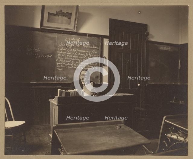 Portrait of a male mathematics teacher with moustache seated at his classroom desk, about 1900. Creator: Unknown.
