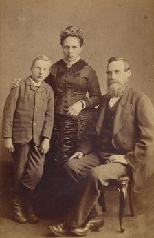Portrait of an unidentified family: mother and son standing, bearded father seated, 1865-1875. Creator: John McKean