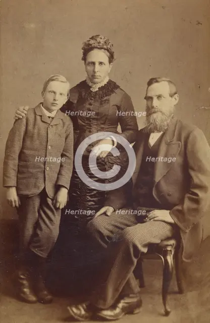 Portrait of an unidentified family: mother and son standing, bearded father seated, 1865-1875. Creator: John McKean.