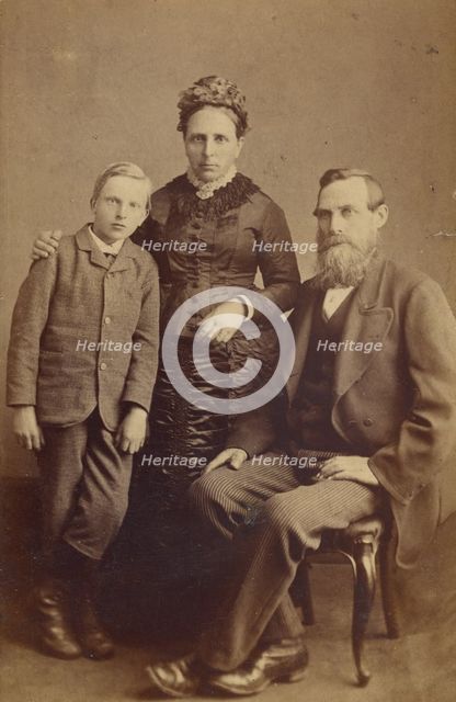 Portrait of an unidentified family: mother and son standing, bearded father seated, 1865-1875. Creator: John McKean.