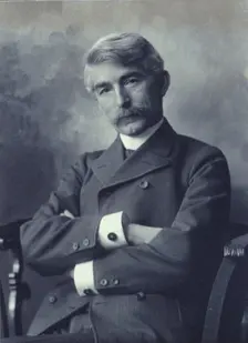 Portrait of man wearing a pinstripe suit seated with his arms crossed, c1900. Creator: Fannie L. Elton
