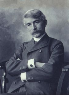 Portrait of man wearing a pinstripe suit seated with his arms crossed, c1900. Creator: Fannie L. Elton
