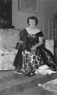 Portrait of seated woman in evening dress with her dog, c1935. Creator: Kirk & Sons of Cowes