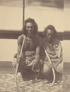 Portrait of Two Native Men Sitting on a Boat Holding Long Curved Sticks, 1865. Creator: Théodule Deveria