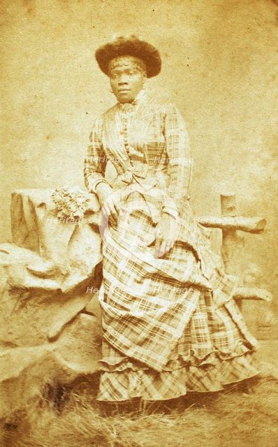 Portrait of unidentified young woman in plaid dress and hat, c1880-c1889. Creator: Thomas Gates.